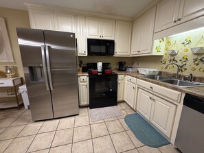 A kitchen with white cabinets, stainless steel appliances, and a patterned backsplash.