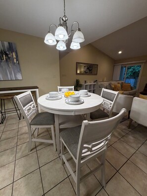 A dining area with a round table, chairs, and a chandelier.