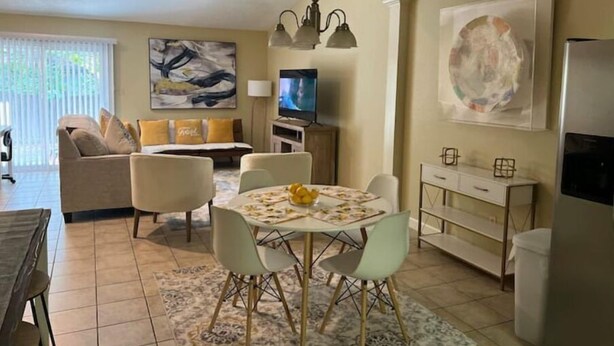 Un salon moderne comprenant un coin repas, un ensemble de canapés, un téléviseur et des œuvres d’art accrochées aux murs.