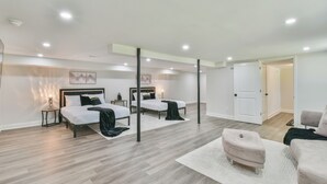 Une chambre moderne avec deux lits, une grande fenêtre et une porte donnant sur une autre pièce.