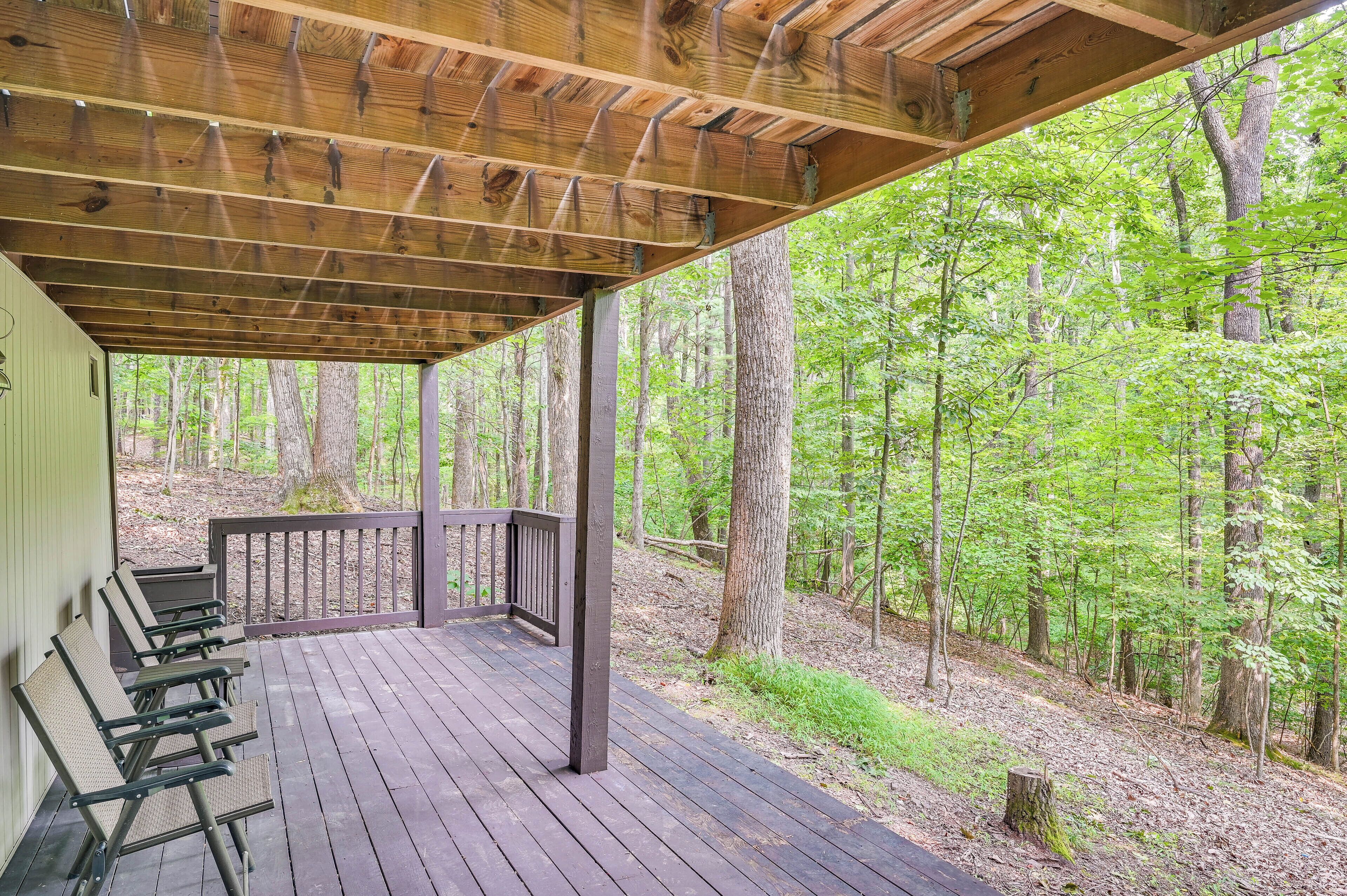 A covered wooden deck with benches, surrounded by a forest.