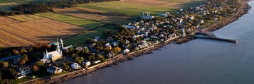 An aerial view of a coastal town with a church, residential houses, and agricultural fields.
