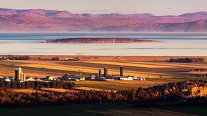 A rural landscape with fields, a small farm, and a body of water. - Auberge Akamaraska (Kamouraska)