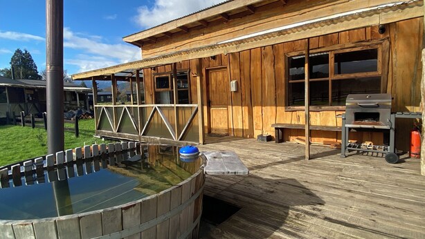 Una construcción de madera con un jacuzzi y una zona de barbacoa.