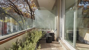 Een modern gebouw met grote glasramen, een houten vloer en een kleine tuin met struiken.