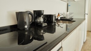 Een keuken met een koffiezetapparaat, een waterkoker en een spoelbak.