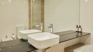 Een moderne badkamer met twee wastafels, een douchecabine met glazen wanden en een grote spiegel.