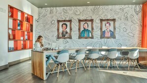 A modern reception area with a wooden desk, multiple chairs, and a patterned wall with framed portraits.