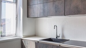A modern kitchen with a window, a sink, and wooden cabinets. - GuestHost - Verona Central Apartment with Balconies! (Verona)