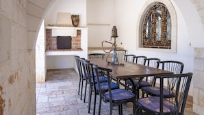 Un comedor con chimenea de ladrillo, una mesa con sillas y un ventanal decorativo.