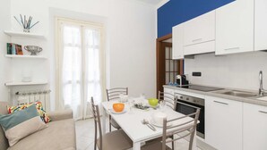A compact kitchen with white cabinets, a dining table, and a sofa. - GuestHost - Functional apartment perfect for 4 guests located in a strategic and well-served position, in the heart of the Lingotto area, ideal for work, tourism and study. We are just a few minutes from the hospital area (Molinette, San Lazzaro Dermatol (Torino)