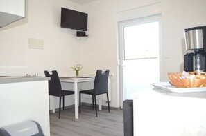 A modern kitchen with a dining table, chairs, a TV mounted on the wall, and a basket on the counter. - Sea View Apartment Marijane, 940 (Preko)