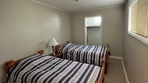 A bedroom with two beds, a ceiling light, and a window with blinds. - Cozy house ON the ATV/ORV trail located in Newberry.  Great for year round fun.  (Newberry)