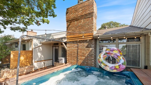 Een hottub met een opblaasbaar ring in vrolijke kleuren, een bakstenen schoorsteen en een houten terras.