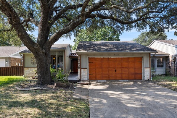 A single-story house with a garage, a large tree in front, and a well-maintained lawn. - Go jump in the Lake-Ray Hubbard (Rowlett)