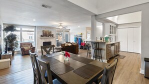 Een ruime woonkamer met een open haard, een eetgedeelte met een grote tafel en een keuken met moderne kasten.