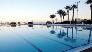 A clear swimming pool with a tiled edge, palm trees, and a view of the sea. - Chalet In Solemar, Generator is Included, Parking, Wifi (Jounieh)