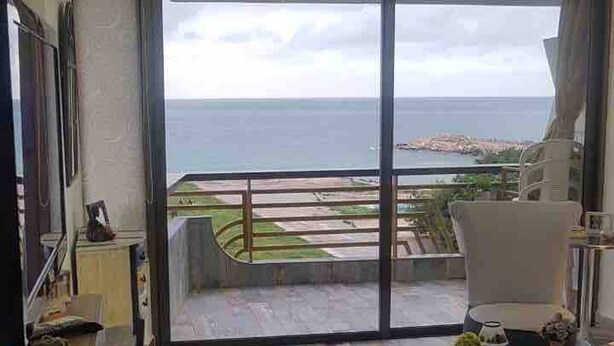 A modern living room with a large sliding glass door leading to a balcony with a view of the sea. - Chalet In Solemar, Generator is Included, Parking, Wifi (Jounieh)