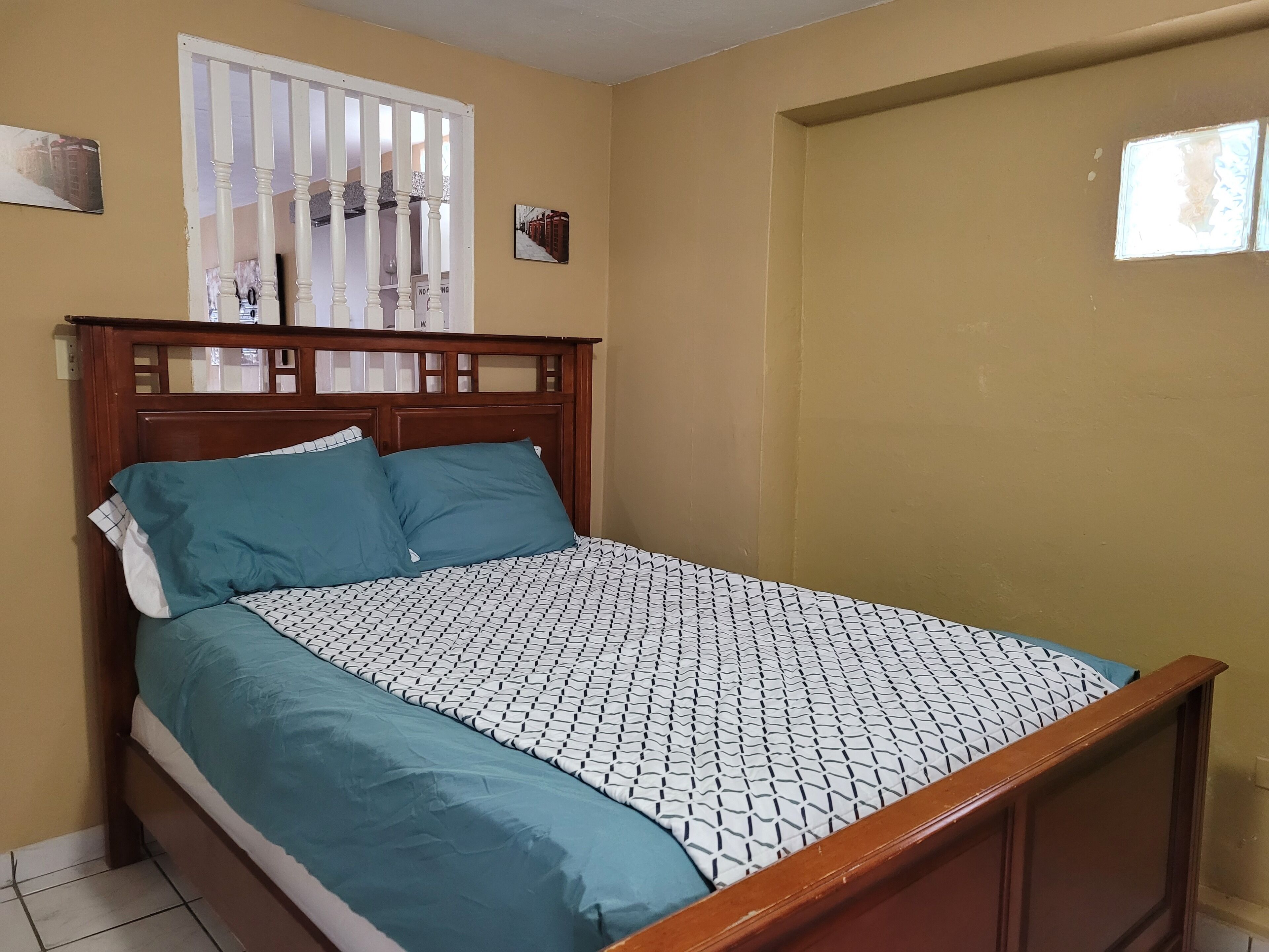 Un dormitorio con estructura de cama de madera, ropa de cama color turquesa y colcha estampada.