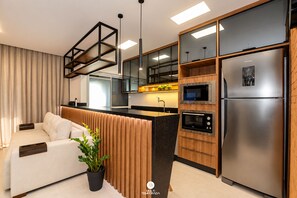 A modern kitchen with built-in appliances, a wooden accent wall, and a black refrigerator.