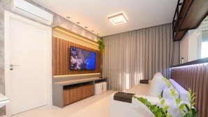 Ein modernes Wohnzimmer mit Flachbildfernseher, einer Couch und einer Pflanze.