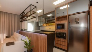 Eine moderne Küche mit integriertem Mikrowellenherd, Backofen und Kühlschrank. Es gibt eine Holz Arbeitsplatte und einen Blumentopf.