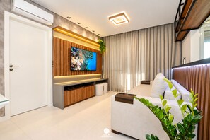 A modern living room with a flat-screen TV, a sofa, and a wooden entertainment unit.