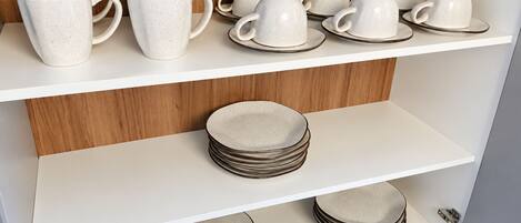 A kitchen with white shelves displaying ceramic mugs and plates.