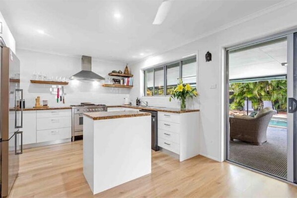 Enjoy cooking in this well-equipped kitchen with a central island, stainless steel range hood, and access to an outdoor area.
