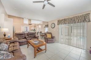 A spacious living room with leather sofas, a wooden coffee table, and a ceiling fan. - Treat Yourself, Luxury Pool & Spa Private Home 16147 (Clermont)