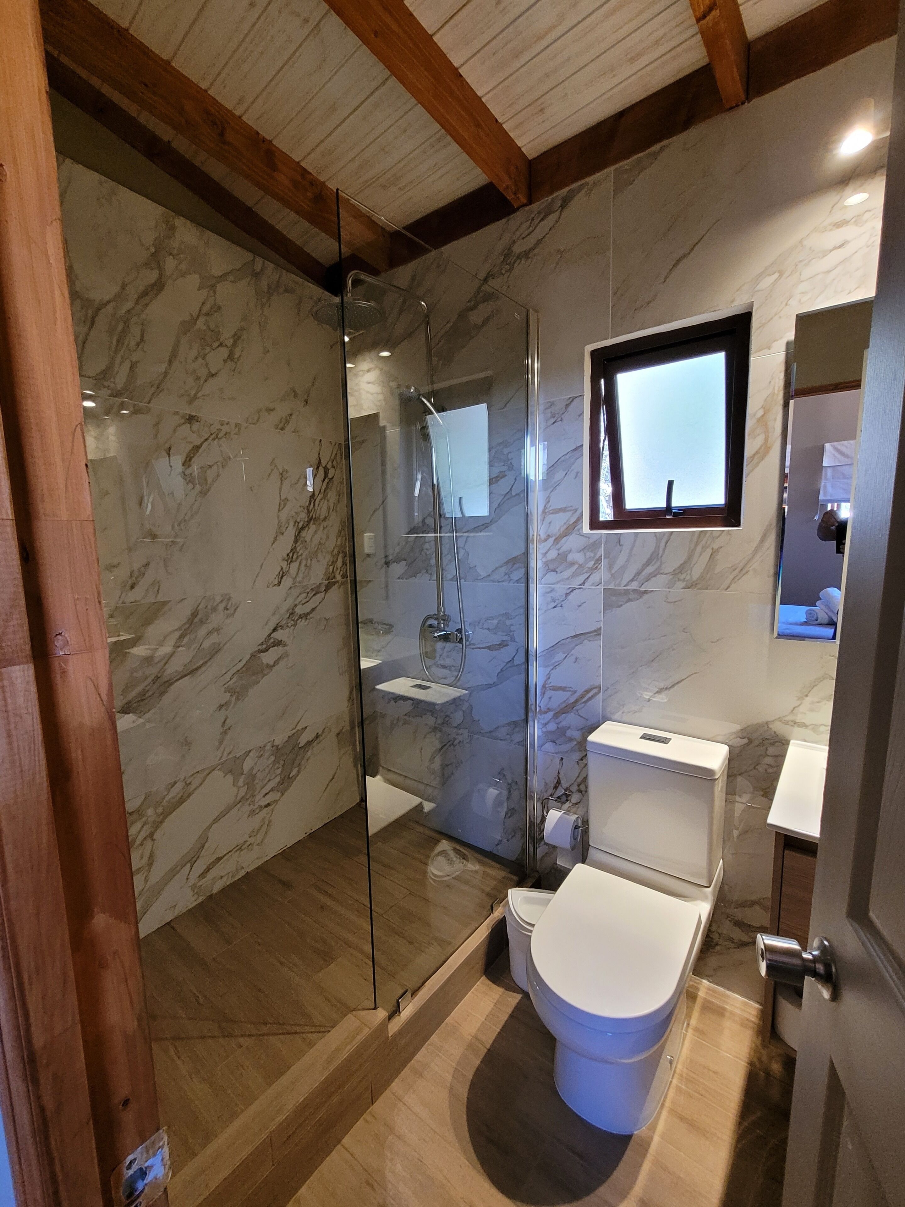 A bathroom with a glass-enclosed shower, a toilet, and a sink.