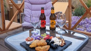 Una mesa de vidrio con comida y bebidas en una terraza con vista a la montaña.