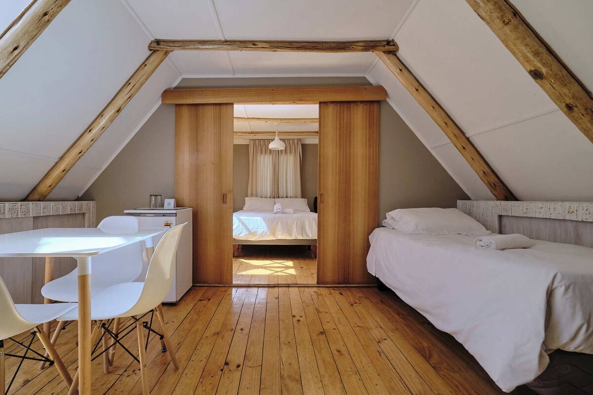 Una habitación con techo de madera, una cama, un escritorio y una silla.