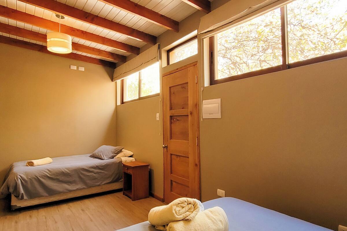 Un dormitorio con dos camas, vigas de madera, una ventana y una puerta.