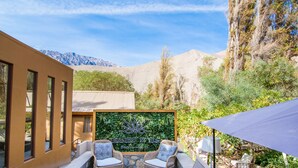 Un patio con mobiliario de mimbre, una pared de piedra y un letrero que dice 'Hotel de Elga'.