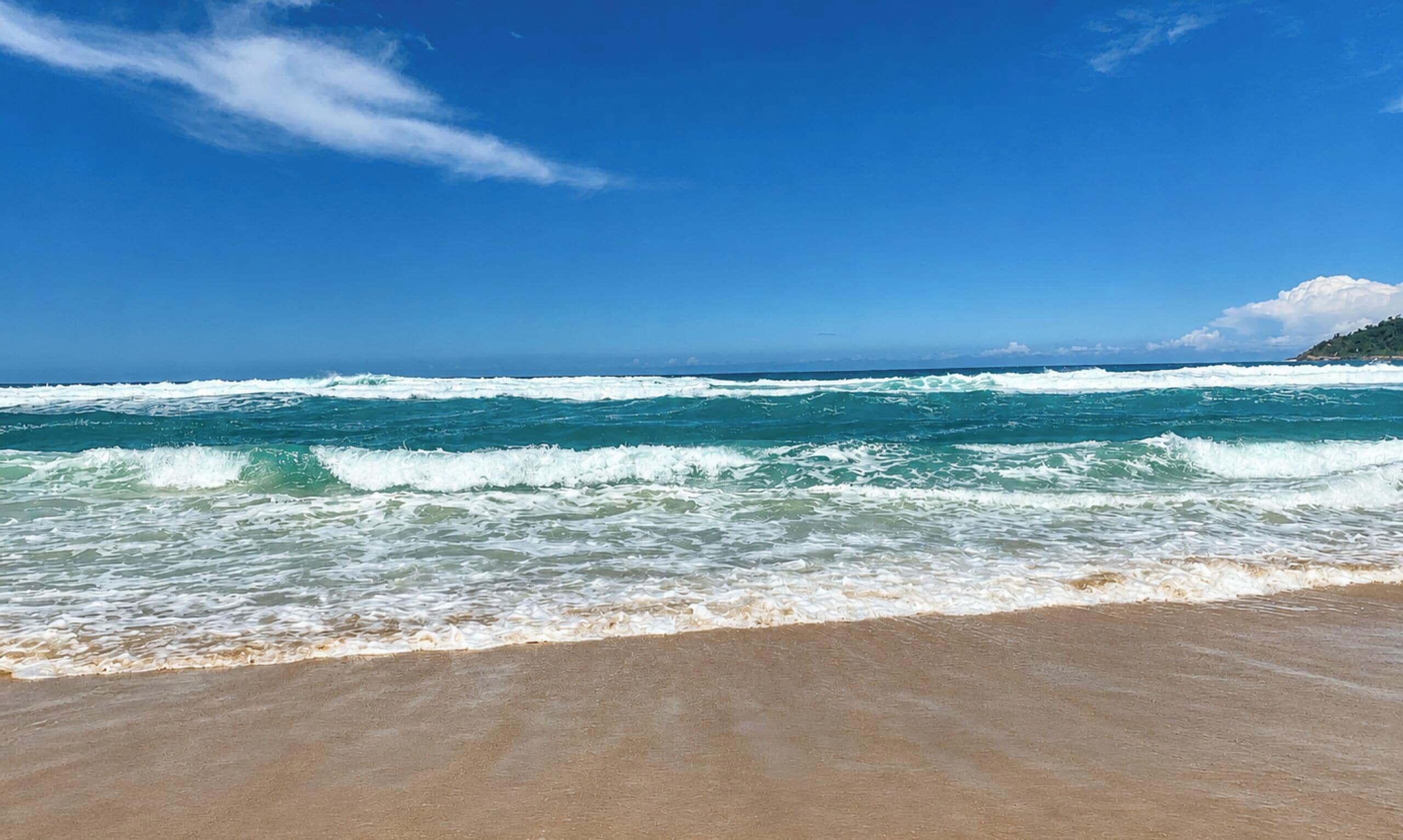 A beach with waves and a clear sky.