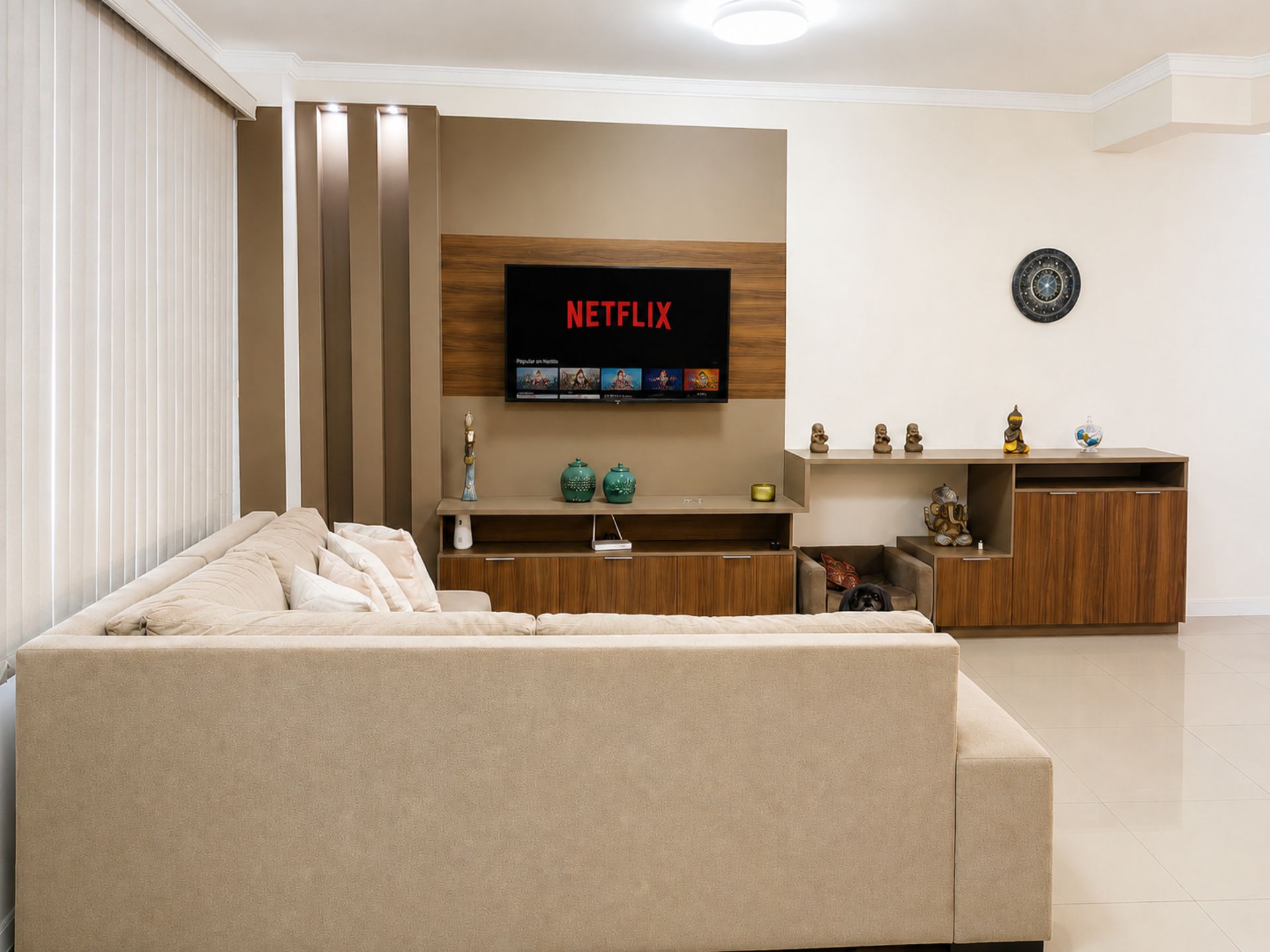 Una sala moderna con un sofá color beige, un mueble de entretenimiento de madera y un televisor de pantalla plana mostrando el logotipo de Netflix.