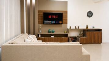 Una sala moderna con un sofá color beige, un mueble de entretenimiento de madera y un televisor de pantalla plana mostrando el logotipo de Netflix.