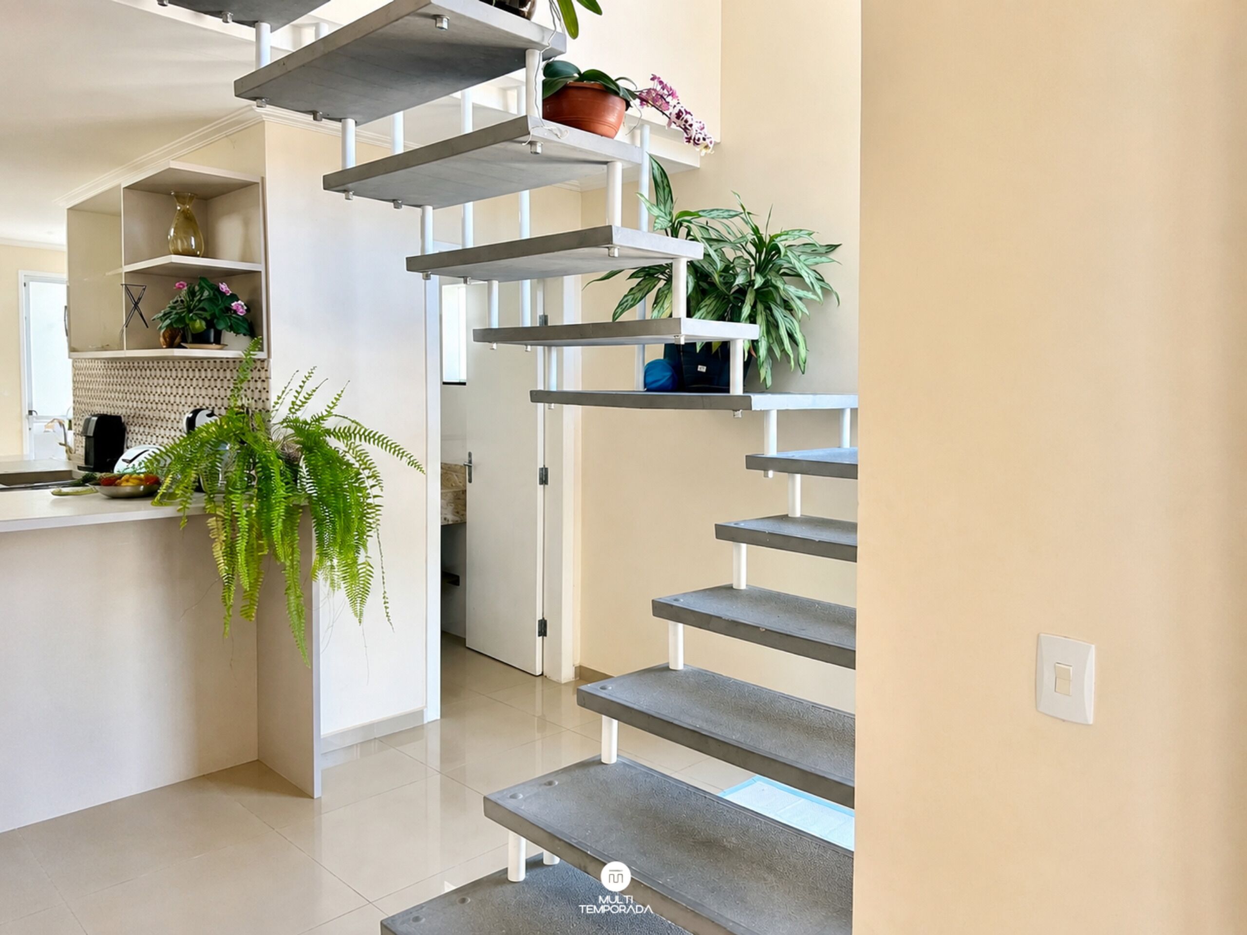 A modern kitchen with white cabinets, a built-in oven, and a hanging plant.