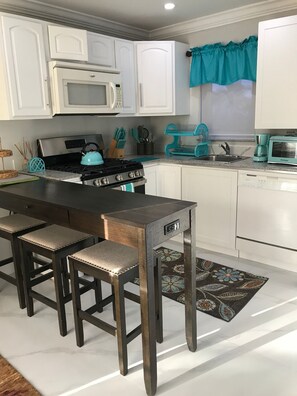 A kitchen with white cabinets, a stove, a microwave, a toaster, and a sink. - The Havens Hideaway (Freeport)
