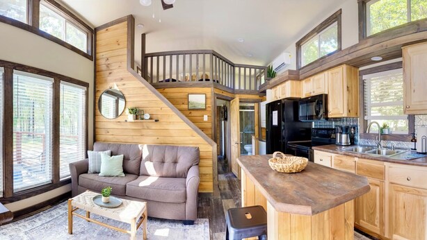 Une cuisine moderne avec des meubles en bois, un réfrigérateur noir et un plan de travail sur lequel se trouve un panier.