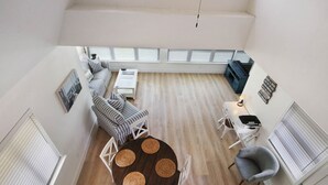 Un vaste espace de vie comprenant une table ronde, un ensemble de canapés et un meuble pour la télévision.