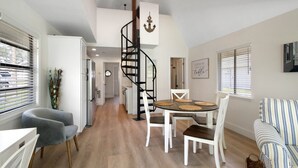 Une cuisine moderne dotée d’un îlot central, de meubles blancs et d’un escalier en colimaçon menant à un niveau supérieur.
