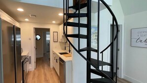 Une cuisine moderne avec un escalier en colimaçon, un plancher en bois et une vue sur le paysage urbain.