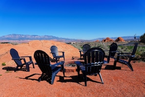 A group of Adirondack chairs arranged on a gravel surface with a view of red rock formations and distant mountains. - Roadrunner: Private Swim Spa + Golf + Sand Dunes (Hurricane)