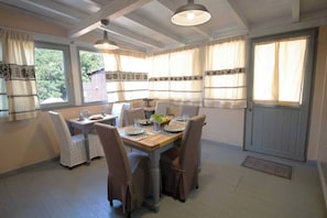 A dining area with a wooden table, four chairs, and a ceiling fan. - Laribiancos, Villasimius, Villa With Sea View (Sinnai)