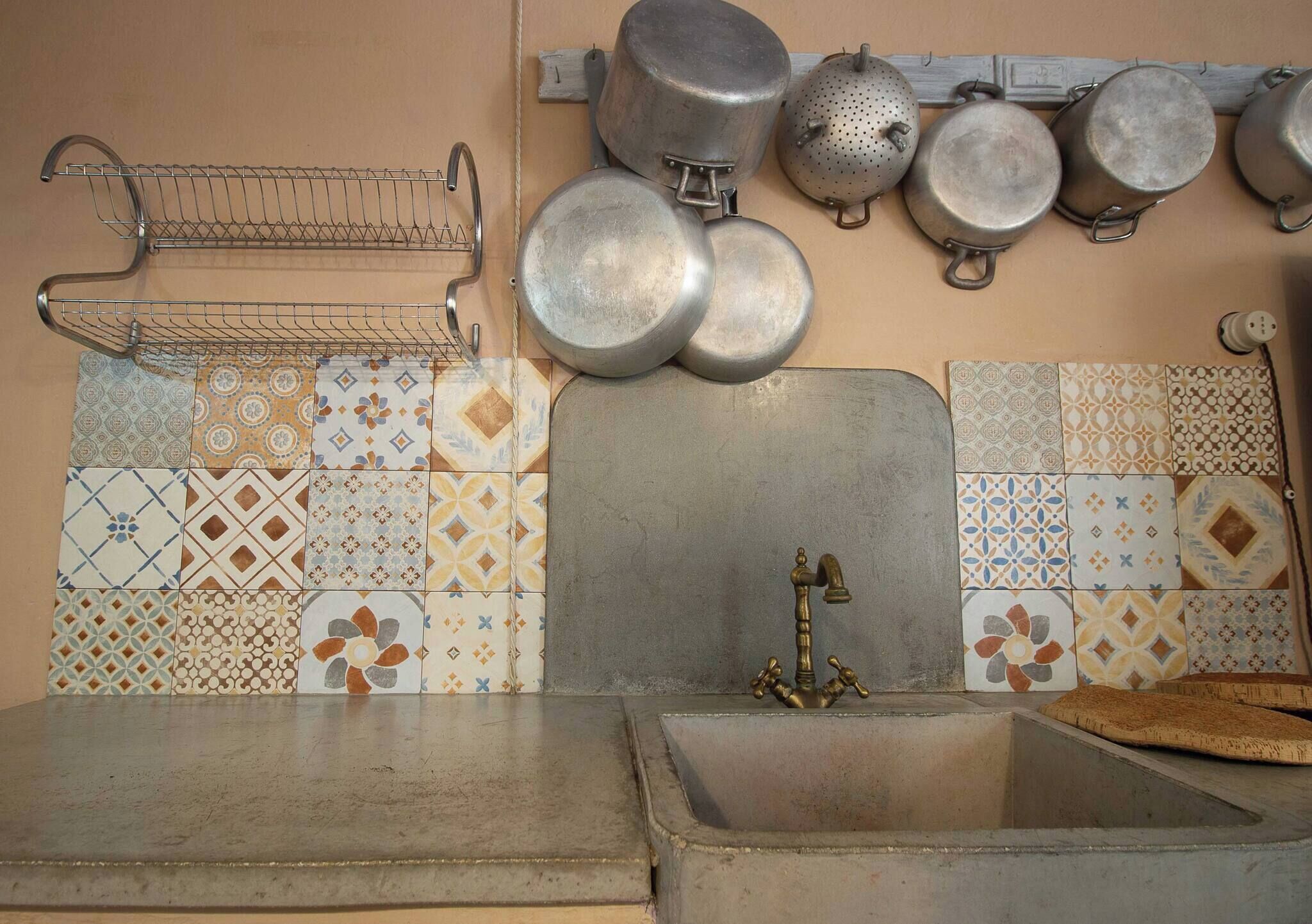 A kitchen with a sink, a metal rack, and various pots and pans.