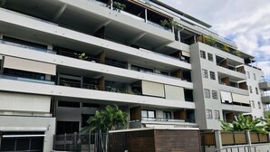 A multi-story residential building with balconies, a gated entrance, and a small wooden structure at the base. - Tipanie- Apt F2 PPT w/pool, A/C, high speed Wifi and wonderful view (Papeete)