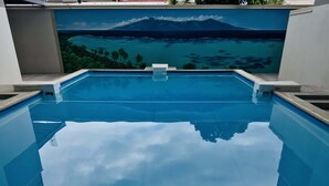 A clear view of a swimming pool with a mural of a tropical landscape in the background. - Tipanie- Apt F2 PPT w/pool, A/C, high speed Wifi and wonderful view (Papeete)