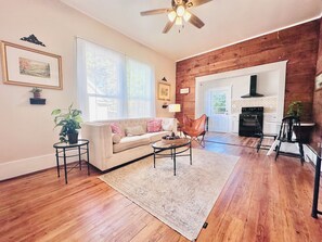 A living room with a sofa, coffee table, and chairs, wooden flooring, and a kitchen in the background. - Walk to downtown, spas, shops & bike trails- stylish, affordable, pet friendly (Hot Springs)